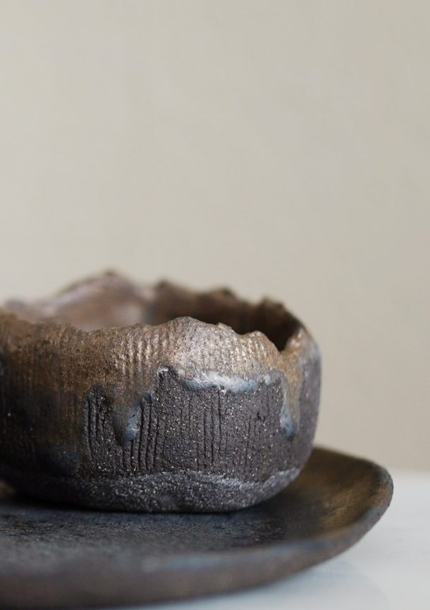 Große, dunkle Keramikvase aus Steinzeugkeramik auf einer Marmorplatte.